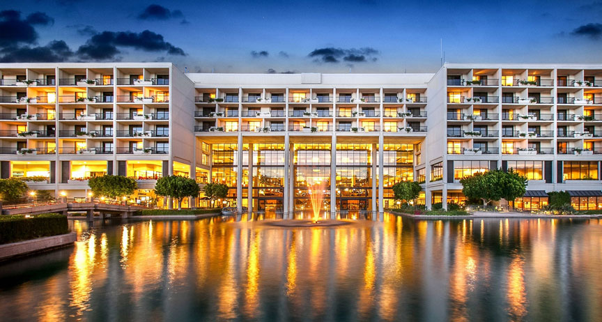 Resort hotel illuminated at dusk above a reflecting pool