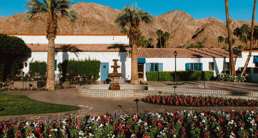 Spanish-style resort courtyard with a tiled fountain and desert mountains behind