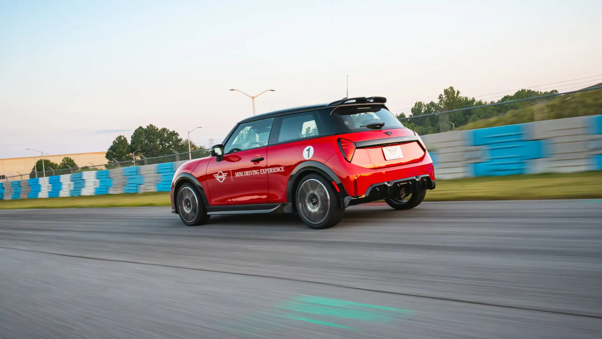 Red MINI Driving Experience car cornering past blue and white track barriers