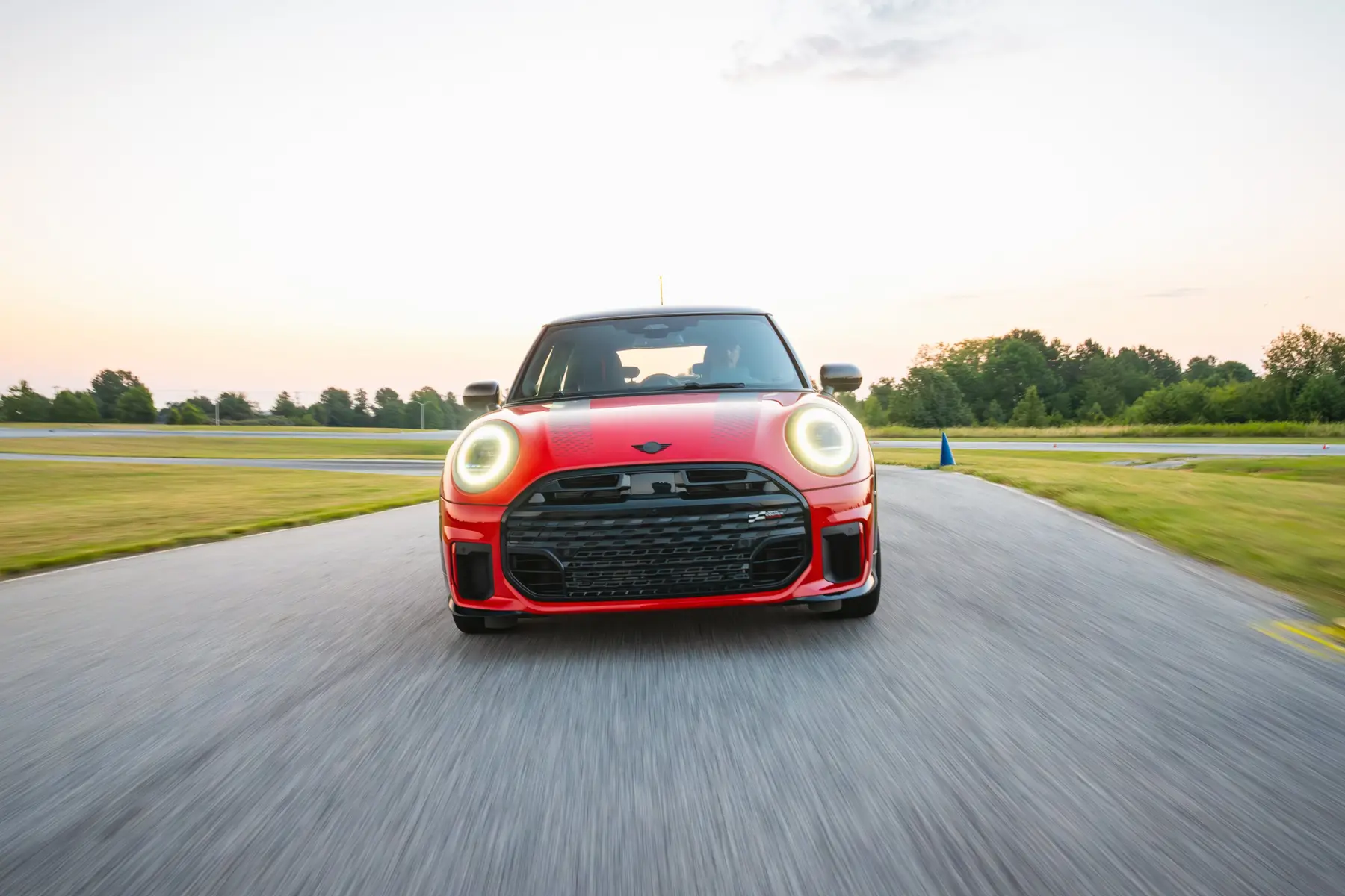 Red MINI head-on at speed with headlights lit on the driving school circuit