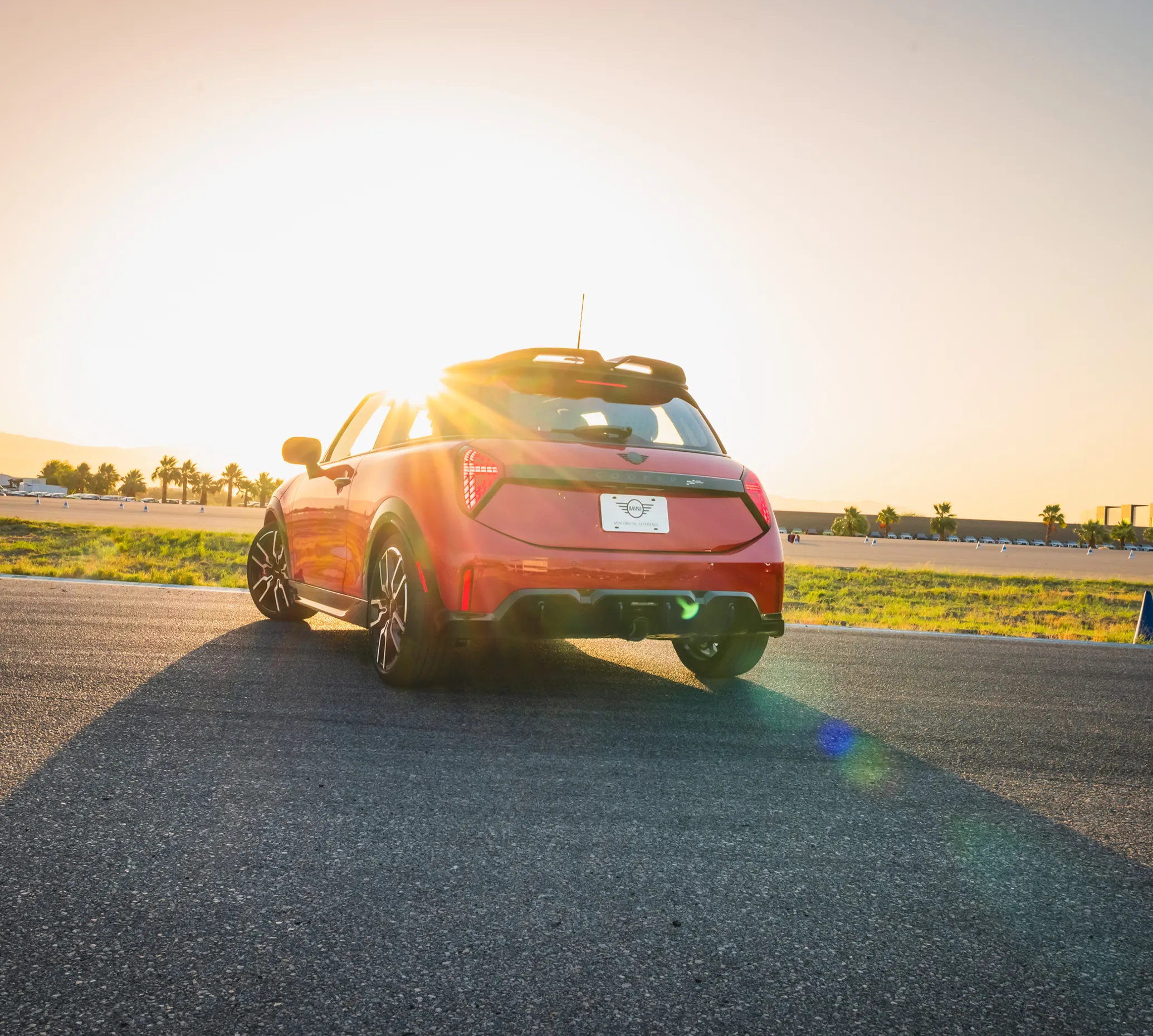 Red MINI on the desert circuit facing into a low sun